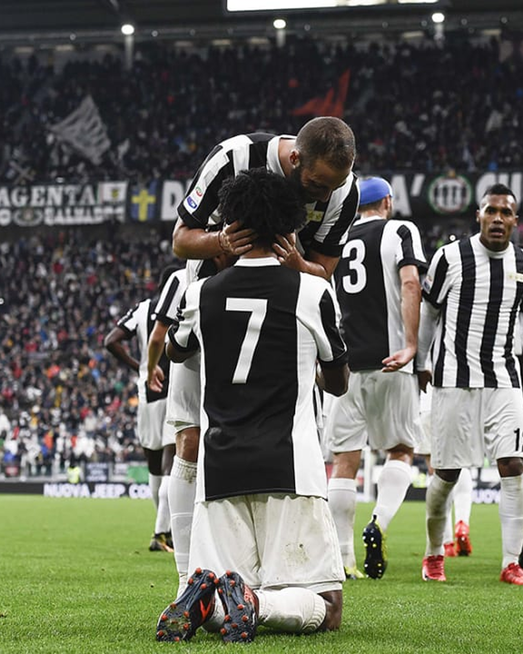 Juan Cuadrado on his knees wearing Juventus 120th Anniversary home jersey