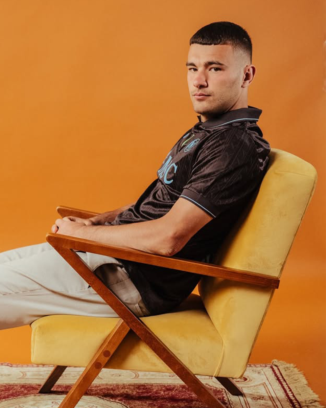 Alessandro Buongiorno sitting on an armchair wearing Napoli 2025-2026 home kit