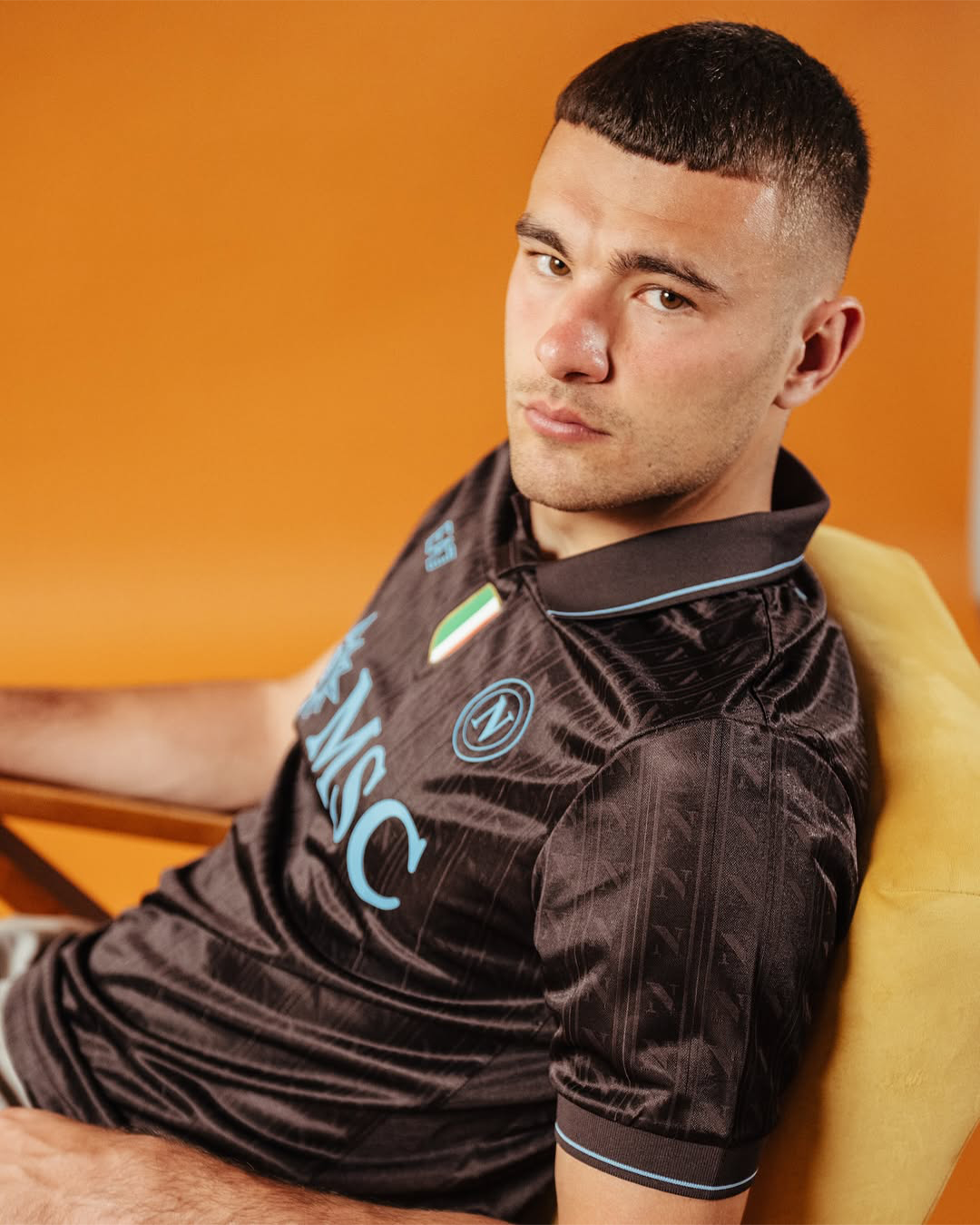 Alessandro Buongiorno sitting on an armchair wearing Napoli 2025-2026 home kit