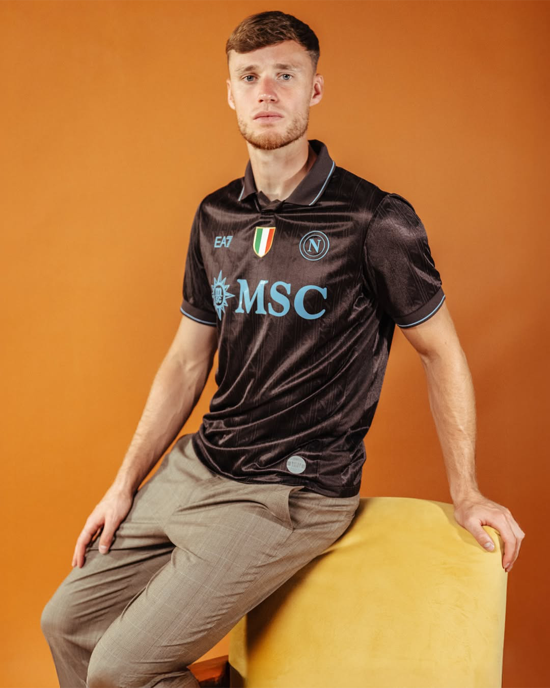 Sam Beukema sitting on an armchair wearing Napoli 2025-2026 home kit